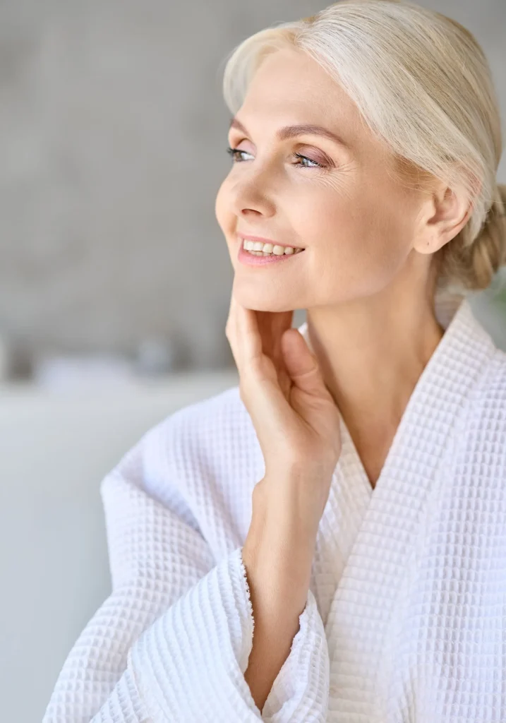 a woman in a white top and blonde hair looking on her side