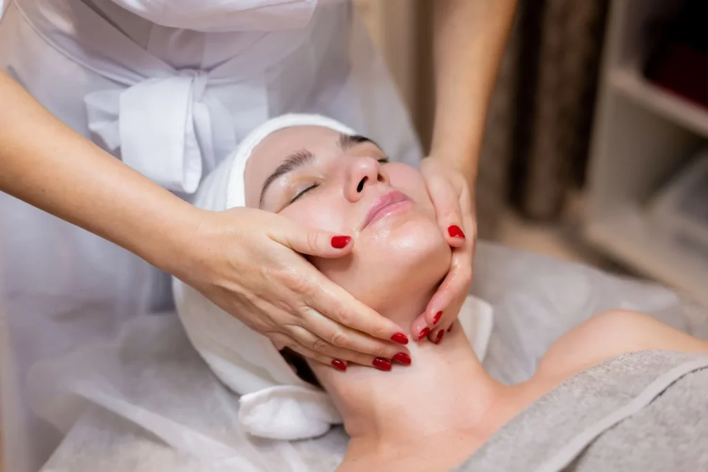 A woman is getting a facial massage at a spa.